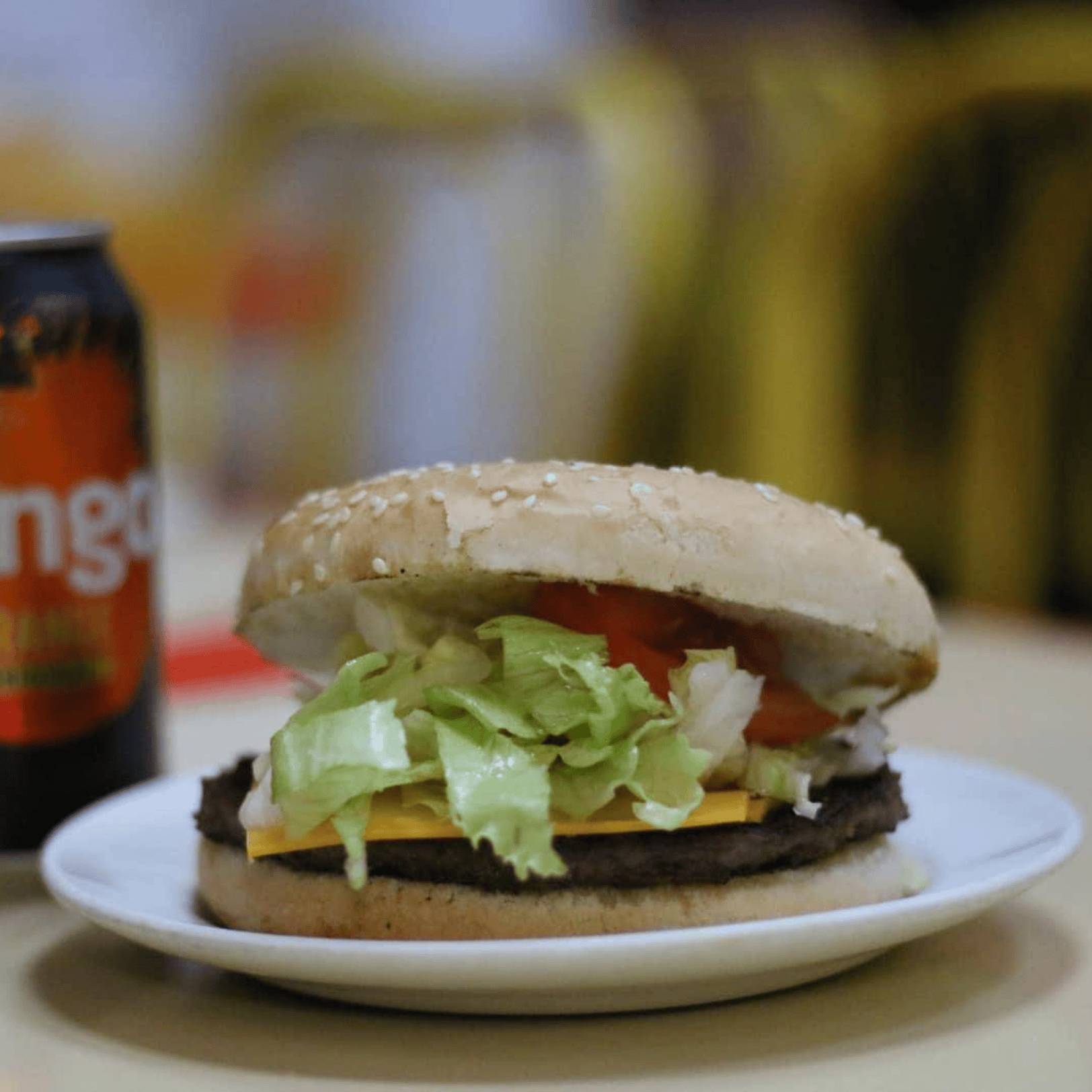 Get Stuffed’s sesame seed bun cheeseburger with lettuce and tomato, and a soft drink can 
                      nearby.