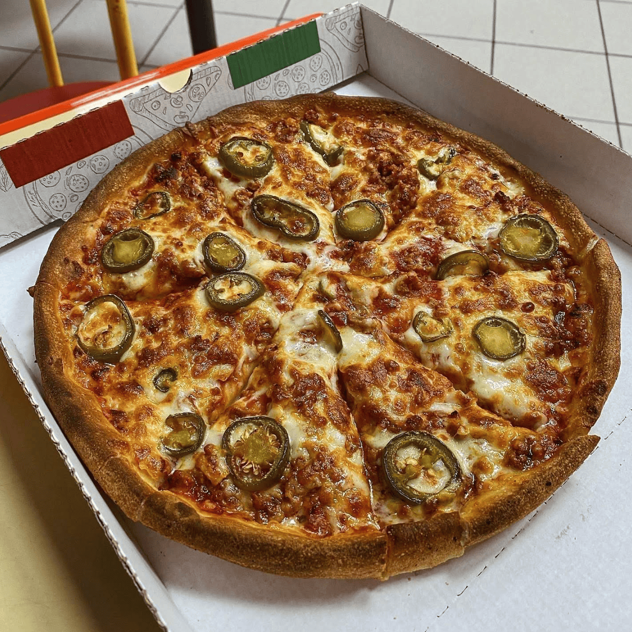 Pizza from Get Stuffed in Newcastle, topped with melted cheese, meat, and jalapenos.​